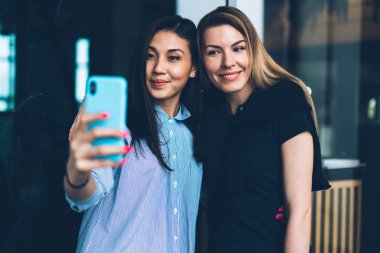 Güzel başarılı kadın arkadaşlarım sosyal ağlarda paylaşım için smartphone kamera selfie yapma modaya uygun kıyafet giymiş. Şirin olumlu hipster kızlar alarak resim yaparken eğleniyor