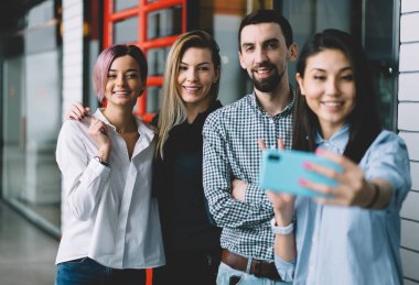 Selfie cep telefonu kamera serbest zaman sırasında ofiste yaparken eğlenmek mutlu erkek ve başarılı çekici kadın. İyi görünümlü duygusal hipster adamlar alarak birlikte kapalı duran resim