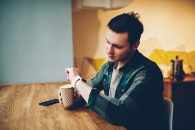 Kahve molası, modern giyilebilir Gadget'ı bildirim app eğlence kafeteryasında harcama dokunmatik ekran üzerinde düzenleme denetimini kullanarak teen hipster adam zamanında yönetme smartwatch bakarak Genç adam