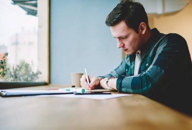 Çalışan işlemi, ödev görevleri yerine getirmeye ve notlar bilgi üniversite sınavlarına hazırlık akıllı hipster adam yaratıcı erkek tasarımcı çizim kroki kafe iç oturan konsantre