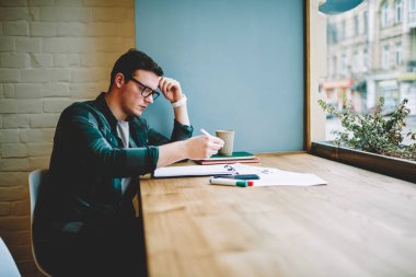 Dalgın hipster adam notings ve muayene, zeki genç erkek kişi kafe proje görevleri tamamlamak için liste yapmak için kontrol için ders kitapları bulunan bilgileri öğrenme alanı coworking eğitim