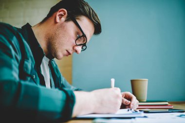 Zeki öğrenci bilgi ve yaratıcılık kullanarak başlatma deyim fikir için muhasebe yaparak öğrenme, ciddi hipster adam konsantre ödev görev için kompozisyon gözlük görünümünü kapat