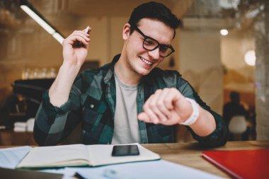 Hippi erkek erkeğe yönetme zaman giyilebilir bilgisayar ekran kafede bakarak Ajanda'yı kullanarak gülümseyen yararlı uygulamalar dijital smartwatch dokunmatik ekran, seyir üzerinde neşeli erkek öğrenci memnun