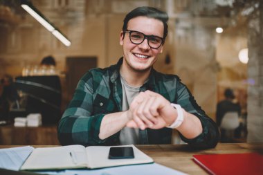 Dijital kol saati öğrenme kafe iç zamanında kontrol gözlük neşeli hipster adam portresi, genç erkek giyilebilir bilgisayar ile memnun mutlu olsun yeni ileti uyarısı