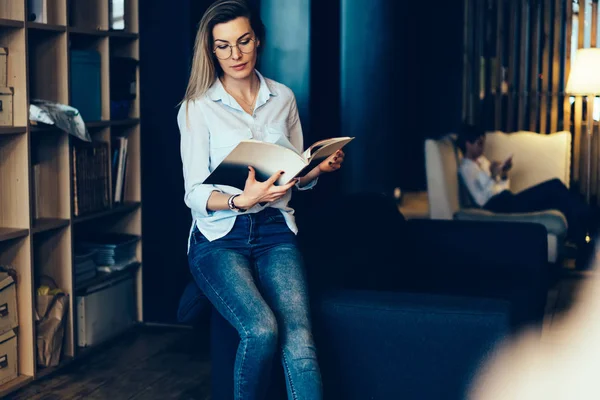 Genç güzel ciddi kadının elinde dergi holding kitaplığında vakit sırasında makalelerinde okuma resim kırpılmış. Şirin düşünceli hippi kız içeride otururken fotoğraf görüntüleme