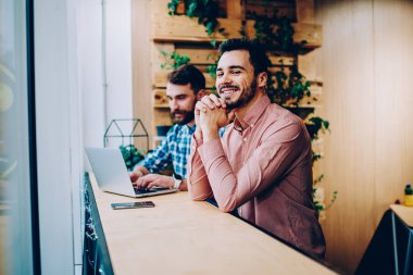 Üniversite kampüsünde başarılı freelancer online başlamak ile arkadaşı ile memnun dizüstü bilgisayarda ödev erkek arkadaşıyla oturan kamera bakarak gülümseyen yakışıklı hipster adam portresi