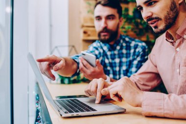 Erkek monitörde işaret eden meslektaşları ile işbirliği dizüstü bilgisayarlara uygulama kurma sırasında tarih seçici odak hipster seçerek öğeleri web sayfası üzerinden netbook üzerinde rezervasyon yaparken çocuklar