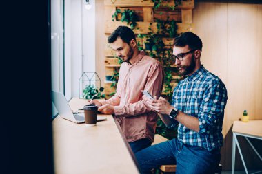 Genç yetenekli erkek bu bilgi için programlama dizüstü bilgisayar ve akıllı telefon üzerinden kontrol üzerinde çalışan geliştiriciler, hipster adam arama numarasına meslektaşı ise cep telefonu üzerinde Web'den Haberler