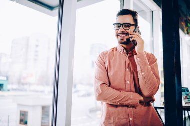 Cep pencere duran, Genç adam tarifeler telefon cep telefonu konuşma bir arkadaşım olması için memnun gülümseyerek telefonu konuşurken rahat kıyafet neşeli hipster adam portresi