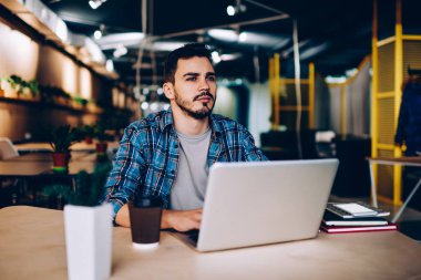 Düşünceli erkek freelancer uzay, netbook ve wifi öğrenme için üniversite kitaplığında kullanarak düşünceli genç öğrenci coworking içinde dizüstü bilgisayar ile oturup çalışma projesi için fikir üzerinde durulması