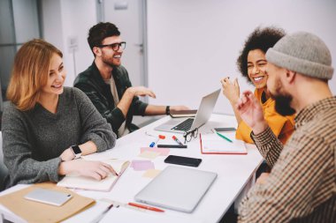 Olumlu erkek ve kadın tasarımcılar gelişmekte olan başlangıç proje teamworking Office için yaratıcı fikirler tartışıyor. Neşeli hipsters öğrenci işbirliği vasıl okul sırası sırasında gülüyor çeşitlilik grubu