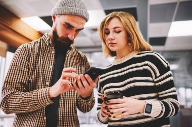 Dalgın sakallı hippi adam kadın blogger Smartphone'da 4 g internet bağlantısı ayarlarını yapma. İki öğrenci kahve molası ayakta Üniversitesi'nde sırasında online eğitsel cep telefonu izlemek