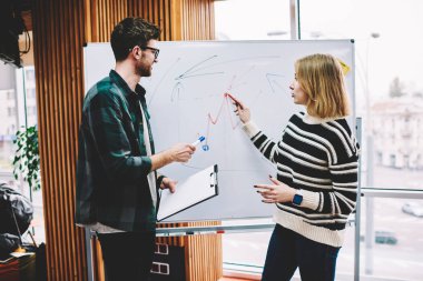 Planı düzeni eğitim oturumu başarılı erkek Koç Üniversitesi'nde tarafından yürütülmesi sırasında flipchart üzerinde yazma akıllı genç kadın. Profesyonel öğretmen gemide hipster öğrenci tarafından çizilmiş grafik denetimi