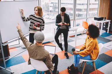 Yaratıcı öğrenciler teamworking fikir ve verimli çalışması için yeni düzenleri tartışırken sunu oluşturma. Genç uzay coworking içinde atölye sırasında flipchart üzerinde grafik çizim hipster çocuklar mürettebatı