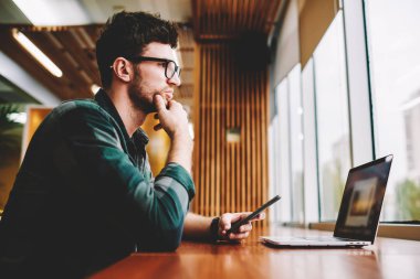 Genç profesyonel bu geliştirici başlangıç için yaratıcı fikirler hakkında durulması vizyon düzeltme için gözlük takıyor. Dizüstü bilgisayarda uygulama yüklerken program planlama sakallı hippi adam