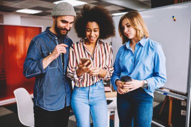 Çeşitlilik grubu başarılı grafik tasarımcıları Web sitesinde smartphone içinde komik video izlerken rahat kıyafet giymiş. Modern teknoloji kapalı ile zaman zevk olumlu erkek ve kadın arkadaş