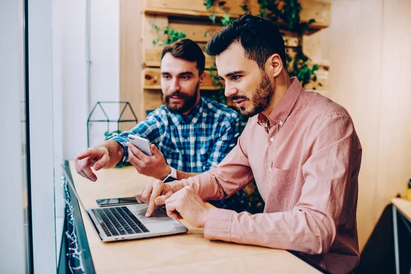 İki erkek meslektaşları üzerinde işbirliği geliştirme projesi uygulaması dizüstü bilgisayar, netbook monitör ofis coworking oturan bilgi hakkında arkadaşıyla danışmanlık işaret hipster adam üzerinde kontrol