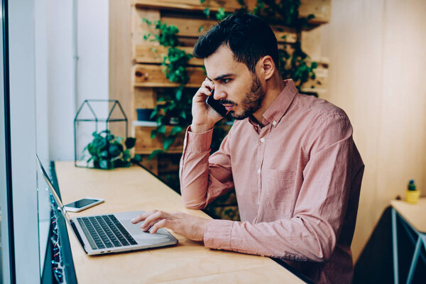 Annoyed male making telephone call to operator helpline having problem with software on laptop computer, angry hipster guy disappointed with getting bill on email banking via cellphone conversation
