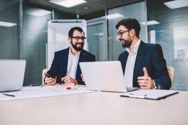 Bilgisayarla iş eğitimi için gülümseyen ve başarılı proje hakkında konuşma sırasında modern elektronik aygıtlar kullanarak uzmanları masada oturma toplantı iş iki ofis çalışanları