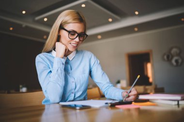 Casual kız Not Defteri'nde yazma gülümseyen genç çekici kız öğrencinin Üniversitesi sınıf ve çizim kroki, neşeli sarışın kadın gözlük kompozisyon içinde oturan fikirle, heyecanlı