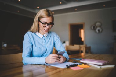 Genç öğrenci kız posta denetleme ve çekici kadınlar online modern cep telefonu kullanarak arkadaşlarınızla sohbet web sitesi yolu ile cellphone, haber okuma Okulu sınıfta otururken gözlük