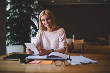Ödev, planlama çalışma süreci yolu ile kullanma taşınabilir pc üzerinde arkadaşlarınızla sohbet için modern Gadget'ı kullanarak kafede oturan kadın yaparken kameraya seyir genç hippi kız portresi