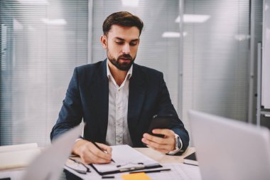 Dalgın gurur CEO'su bilgisi verilerini office iç çalışma smartphone aygıtından yeniden yazma. Sakallı işadamı muhasebe raporları yaparken gelen bildirim telefon üzerinde okuma
