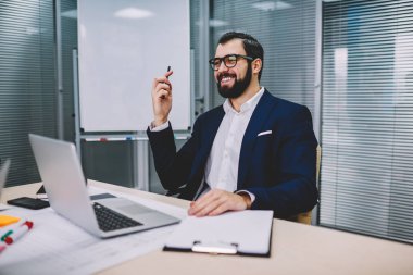 Müreffeh sakallı girişimci tablo modern dizüstü bilgisayar Office ile Toplantı oturan gelişmekte olan iş projesi için komik fikirler tartışılması sırasında gülüyor şık takım elbise giymiş
