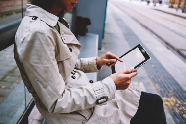 Ücretsiz 4 g internet bağlantısı açık havada tramvay durağı üzerinde oturan yoluyla Web sitesinde online ödeme yapmak için modern tablet boş kopya alanı ekranda dokunmadan parmak ile genç kadın görünümünü yan kırpılmış