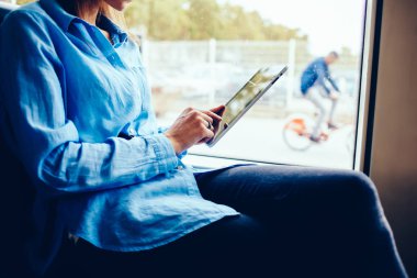 Hippi kız parmak ile modern dokunmatik yüzey toplu taşıma kablosuz Internet bağlantısı kullanarak ekranda dokunmadan yan görünüm kırpılmış. Genç kadın dijital tablet online sohbet metin yazma