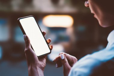Hareket eden telefon ışıklı büyük kopya alanı ile holding kadının eller dokunmatik ekran açık havada akşam bokeh kenti ışık ile. Kadın kişi online alışveriş için smartphone app kullanarak görünümünü kapat