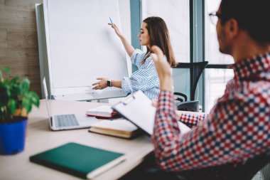İşlem başlangıç proje üzerinde işbirliği sırasında fikirler tartışıldığı flip grafik kullanarak meslektaşlarının erkek çalışan Office, konuşma sırasında oyun tahtasını sahte gösteren genç ciddi kadın