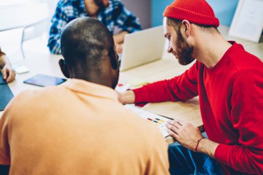 Arkadan görünüm yetenekli çok kültürlü öğrenci ortak görev beyin fırtınası sırasında tablo toplantı oturup birlikte çalışma akıllı rahat kıyafet giymiş. Çeşitli yenilikçi genç insanlar çözüm tartışıyor