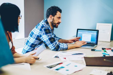 Genç adam bilgi modern dizüstü bilgisayar klavyede yazarak modern ofis tabloda toplantıda çalışma işlemi sırasında meslektaşları ile app tartışırken kablosuz Internet bağlantısı