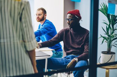 Afrikalı-Amerikalı genç adam masaüstü sınıf toplantıda beyin fırtınası oturmuş akıllı rahat kıyafet giymiş. Üniversitede ders sırasında eğitim görev çözme hipster adam koyu tenli