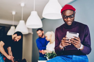 Casual giyim kablosuz 4 g kullanarak modern dokunmatik yüzey üzerinde internet sitesinde bilgi arama olumlu Afrikalı-Amerikalı genç ma takım arka plan üzerinde ortak çalışma arkadaşları ise internet