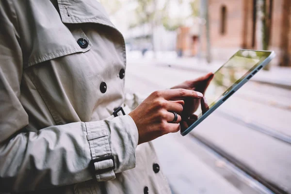 Side cropped view of female person\'s hands touching with finger display of modern touch pad choosing website for search information via 4G internet.Hipster girl making payment online on digital tablet