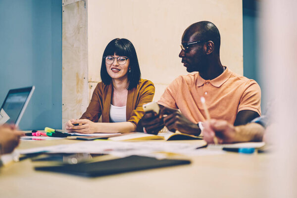 African american young man consulting with female colleague during brainstorming in modern office.Multicultural young people in smart casual wear discussing project and productive strategy of success