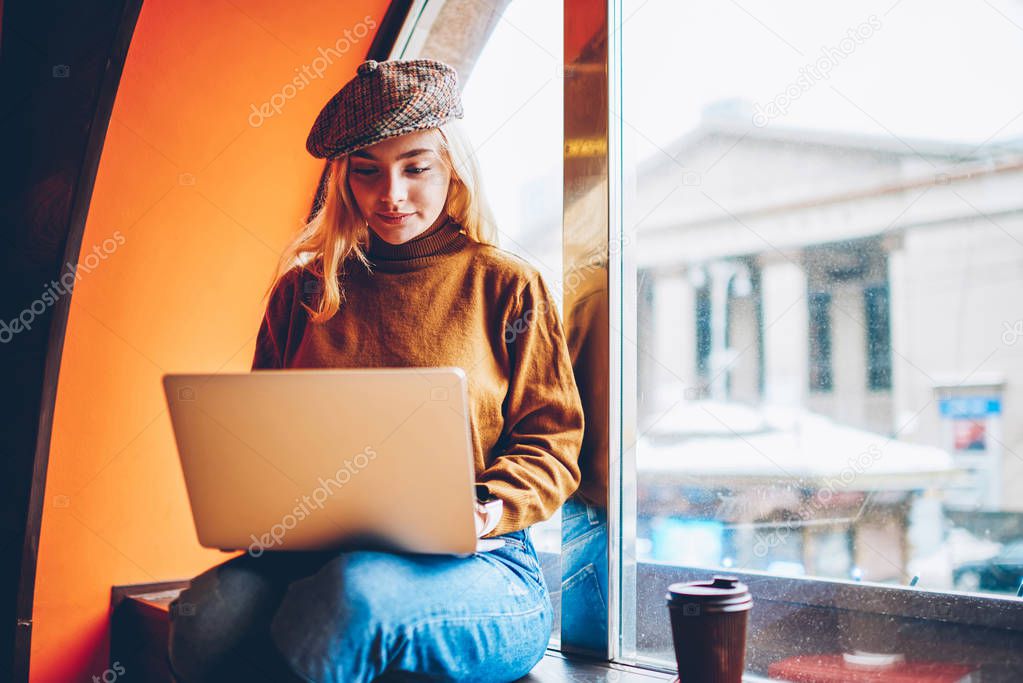 Cute young woman watching studying tutorial on laptop computer during free time in coffee shop,skilled  female freelancer creating content for website publication working remotely on netbook