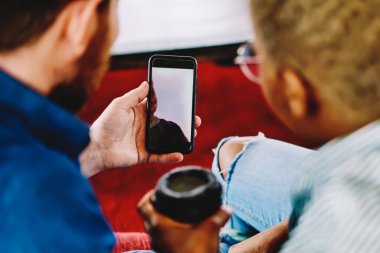 İki çok kültürlü arkadaş 4 g kullanarak Web sitesinde online video izlerken arkadan görünüm kırpılmış modern smartphone cep telefonu ile internet. Telefon elinde tutan ve haber web sayfasında okuma farklı gençler