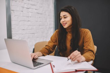 Gülümseyen genç kadın online yön yolu ile öğrenme web seminerleri yazılı görevleri yapmak dizüstü bilgisayarda izleyerek eğitim bilgi online araştırma yapma ve notlar, pozitif kadın serbest meslek