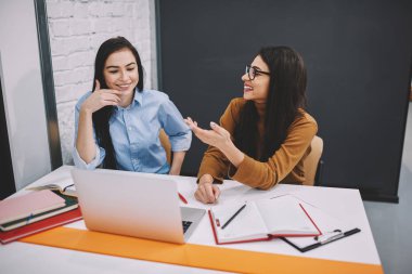 Genç Öğrenciler kurs iletişim ve fikirleri tartışmak dostça işbirliği gülümseyerek konuşuyor ve birbirleri ile şaka proje üzerinde çalışma işlemi sırasında eğlenmek neşeli kadın arkadaşları 