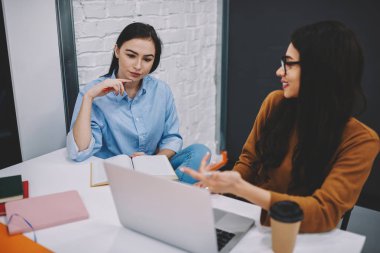 Rapor, yetenekli erkek arkadaşı ile yaratıcı fikir için beyin fırtınası bilgi web sitesinde işaret yapmak için dizüstü bilgisayar kullanan college kampüsünde ders çalışan genç kadın takımı