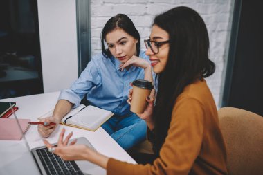 Dizüstü bilgisayardaki bilgilere web birlikte araştırma yapma ve verimli işbirliği olan sayfada işaret meslektaşları tarama proje çözümleri tartışmak profesyonel kadın çalışanların