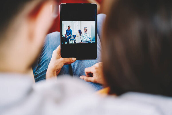 Cropped back view of couple in love watching movie online on touch pad using wireless 4G connection.Young marriage checking email and viewing photos in blog on digital tablet device