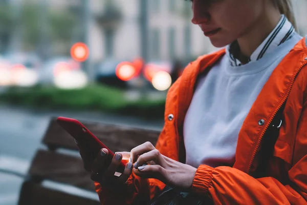 ボケ味がぼやけて光の街に座って赤ケースで若い女性の持ち株のスマート フォンのビューをトリミングしました ソーシャル ネットワークで携帯電話約人テキスト メッセージを介して女性順のタクシー — ストック写真