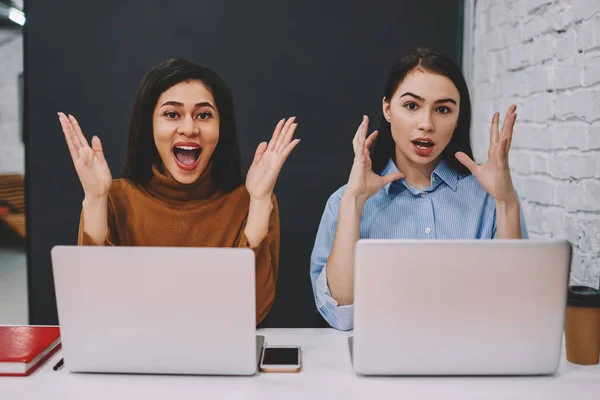 两名时髦的女孩在网上比赛中获胜感到惊讶 坐在膝上型电脑上 女学生震惊于大学假期新闻在校园学习中的信息 — 图库照片