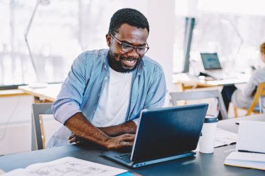 Neşeli Afro-Amerikan erkek öğrenci başarı online iş okumak haber lapto müreffeh erkek freelancer memnun komik film izlerken online yolu ile netbook kampus, süre gülüyor