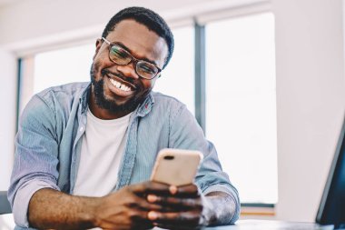 Smartphone cep telefonu ile komik video serbest zaman sırasında iyi bağlantı 4 g zevk mutlu koyu tenli adam komik neşeli Afro-Amerikan hipster adam Internet mobil fon film izlerken için