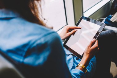 Kadın yolcu dijital tablet ile internet reklamı için kopyalama alanı alanı boş ekranda parmak ile dokunmadan arka görünümü. Modern tablet ile tutarak şarkı seçimi kadının ellerini yukarı alay